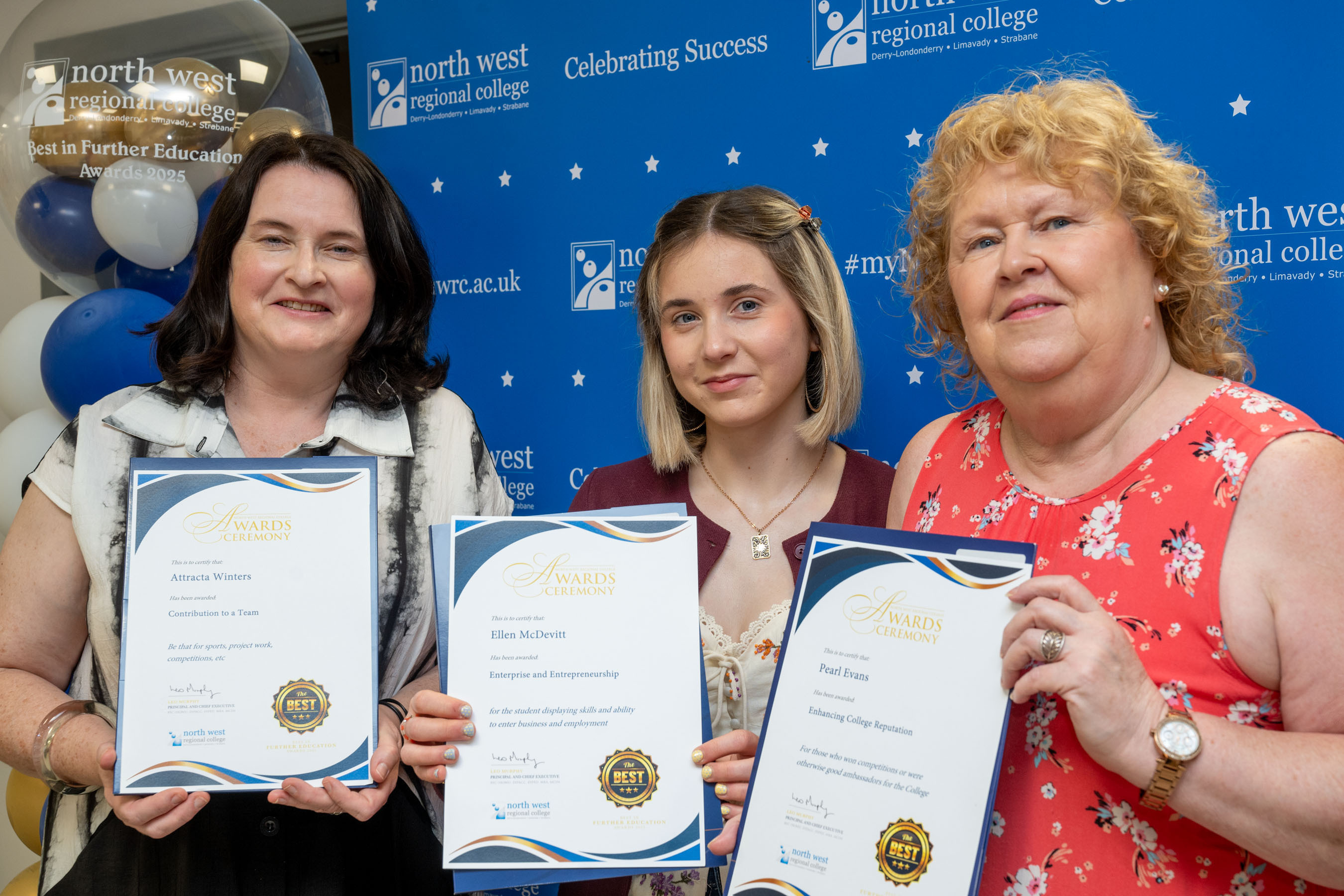 Three people at celebration event all holding certificates
