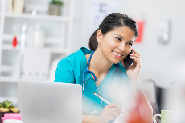 female nurse on the phone sitting at a laptop